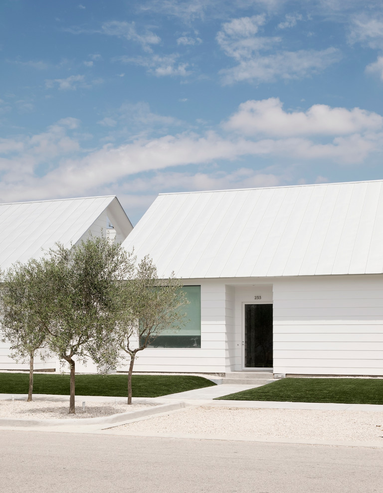 Cette image montre une longère blanche design de plain-pied et de taille moyenne avec un toit à deux pans, un revêtement en vinyle et un toit blanc.