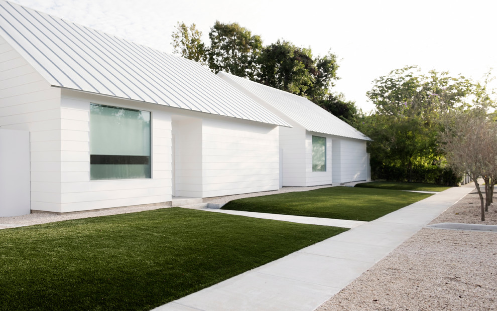 Стильный дизайн: одноэтажный, белый дом среднего размера в современном стиле с облицовкой из винила, двускатной крышей и белой крышей - последний тренд
