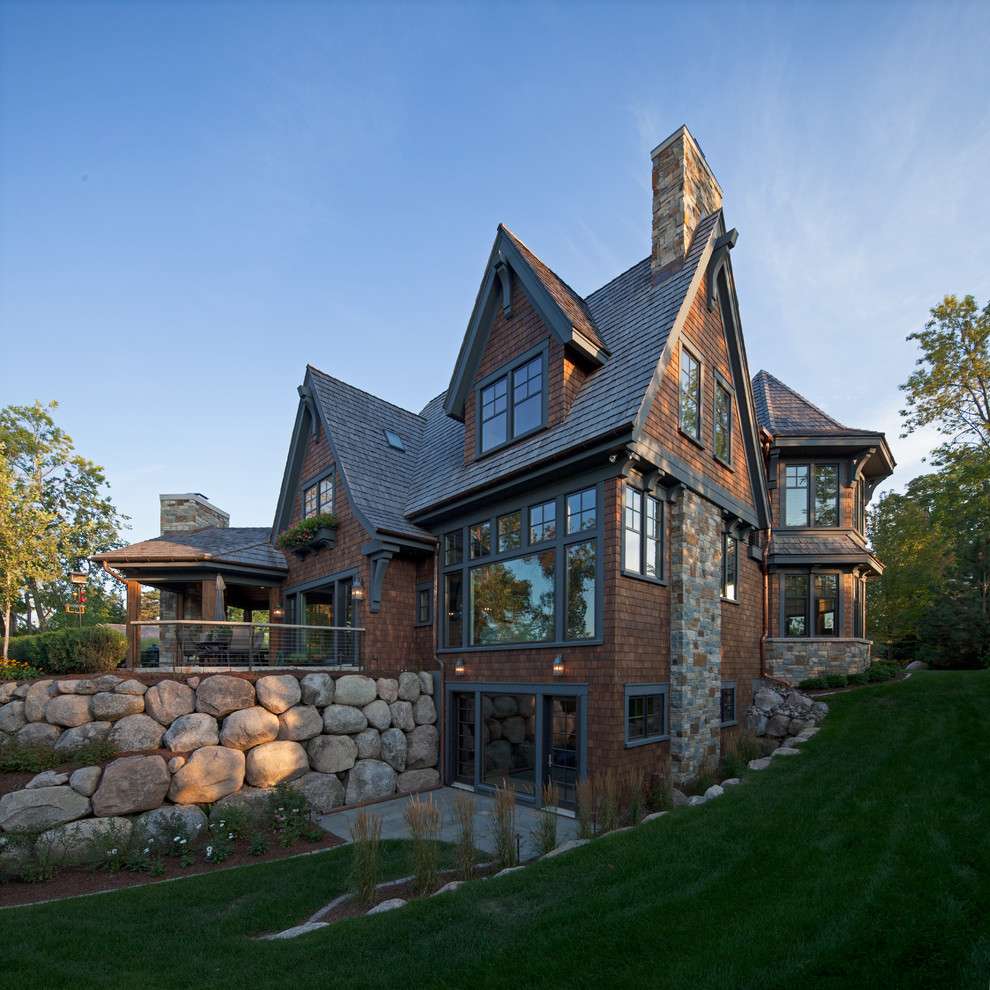 Photo of a large and brown rustic detached house in Minneapolis with three floors, wood cladding, a pitched roof and a shingle roof.