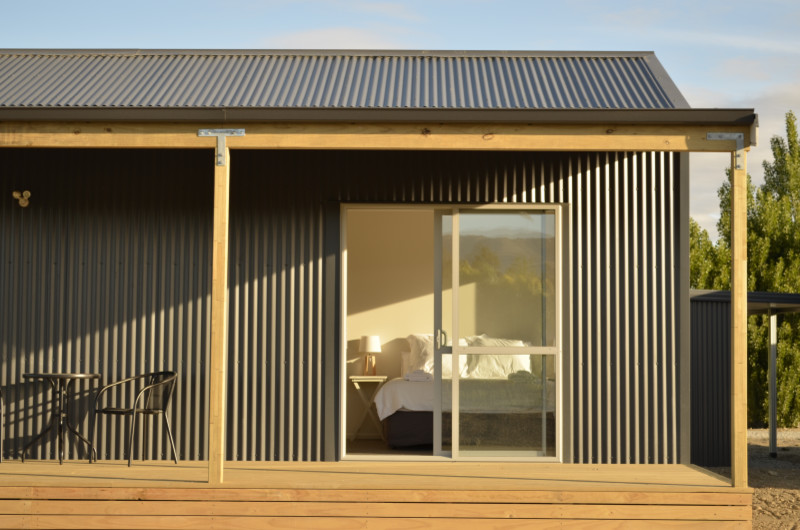 Imagen de fachada gris de estilo de casa de campo pequeña de una planta con revestimiento de metal y tejado a dos aguas