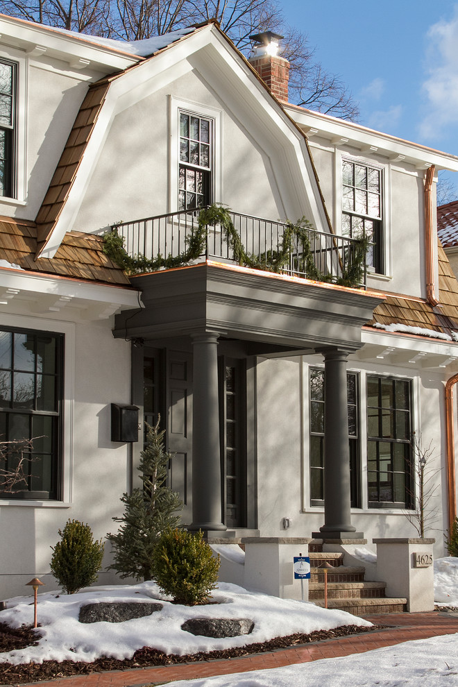 Стильный дизайн: двухэтажный, белый дом в классическом стиле с мансардной крышей и облицовкой из цементной штукатурки - последний тренд