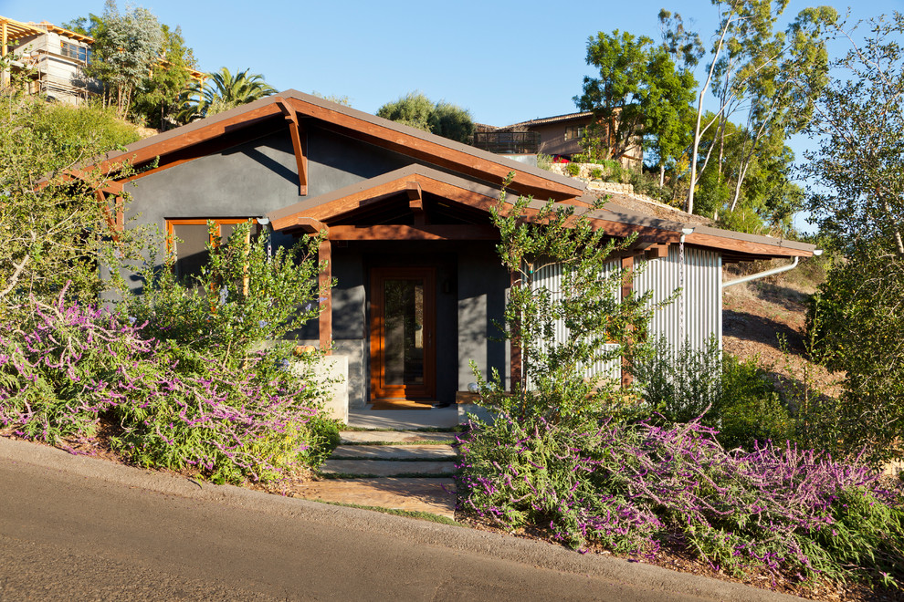 Cette image montre une petite façade de maison grise chalet de plain-pied avec un revêtement mixte et un toit à deux pans.