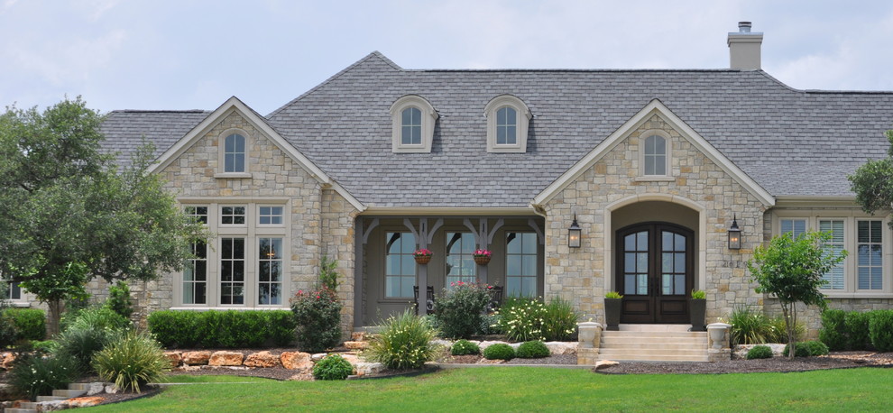 Large traditional beige one-story stone exterior home idea in Austin with a hip roof