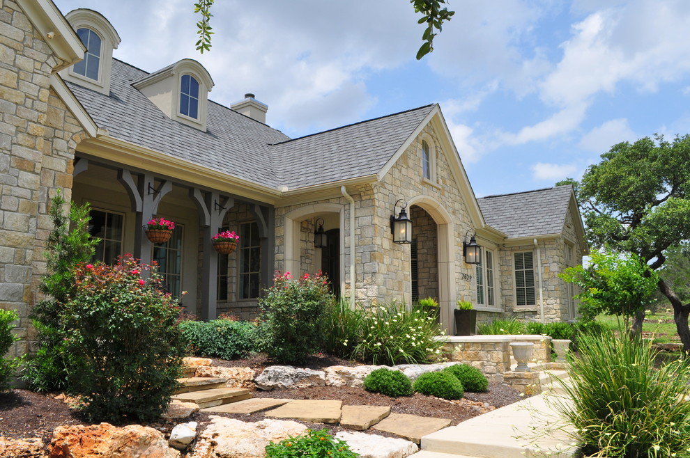 Large and beige classic bungalow house exterior in Austin with stone cladding and a hip roof.