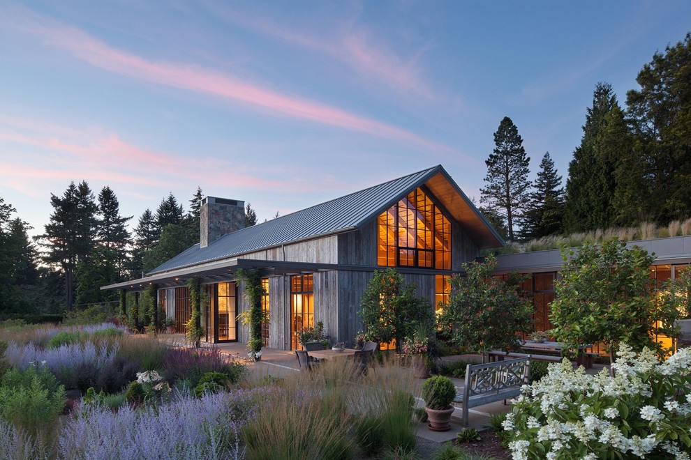 Exemple d'une façade de maison grise nature en bois de plain-pied avec un toit à deux pans et un toit en métal.