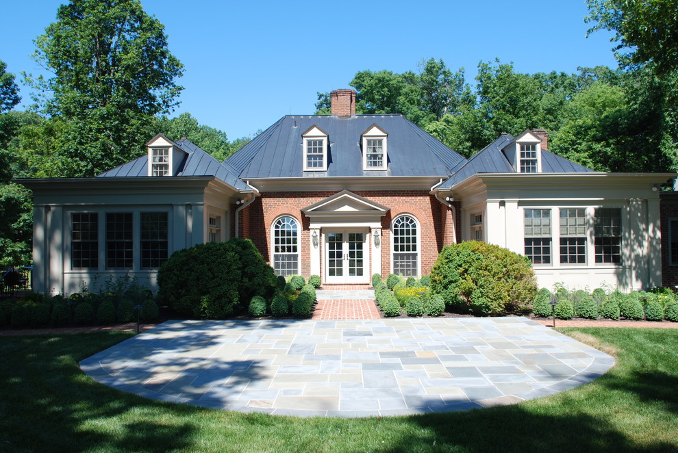 Example of a large classic red two-story brick house exterior design in DC Metro with a hip roof and a metal roof
