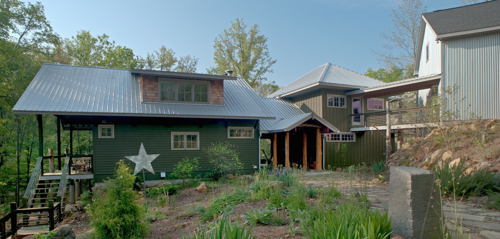 Foto della villa grande verde rustica a tre piani con rivestimento in legno, tetto a padiglione e copertura in metallo o lamiera