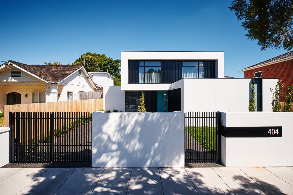 Modelo de fachada de casa blanca contemporánea grande de dos plantas con revestimiento de estuco, tejado plano y tejado de metal
