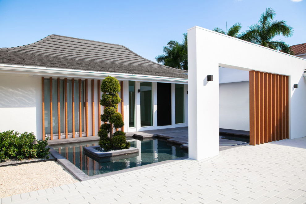 Inspiration for a small 1960s white one-story stucco house exterior remodel in Tampa with a shingle roof