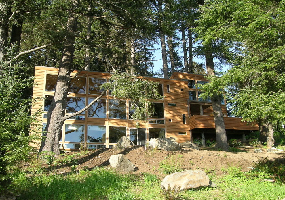 This is an example of a large contemporary house exterior in Portland with three floors and wood cladding.