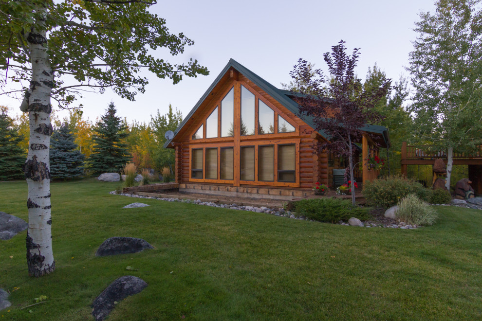На фото: двухэтажный, деревянный частный загородный дом среднего размера в стиле рустика с двускатной крышей и металлической крышей