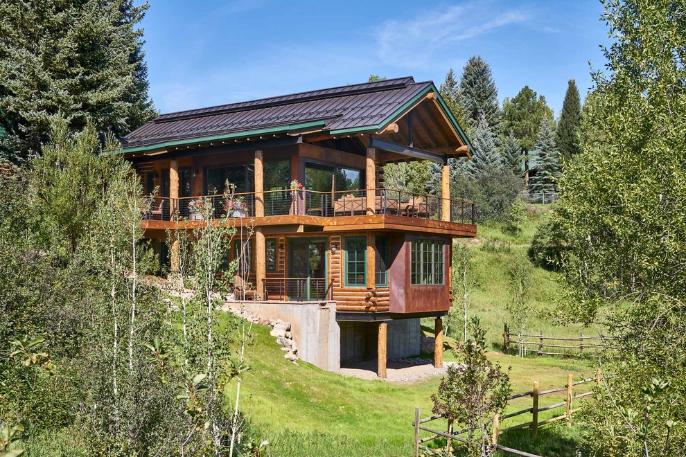 Immagine della villa grande marrone eclettica a due piani con rivestimento in legno, tetto a capanna e copertura in metallo o lamiera