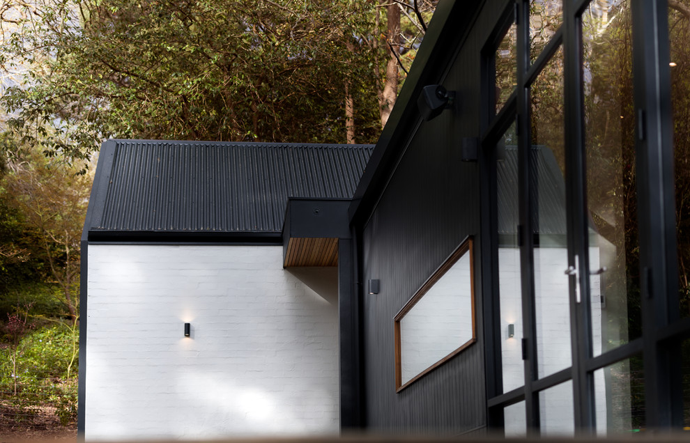 Пример оригинального дизайна: одноэтажный, черный дом среднего размера в современном стиле с комбинированной облицовкой и вальмовой крышей