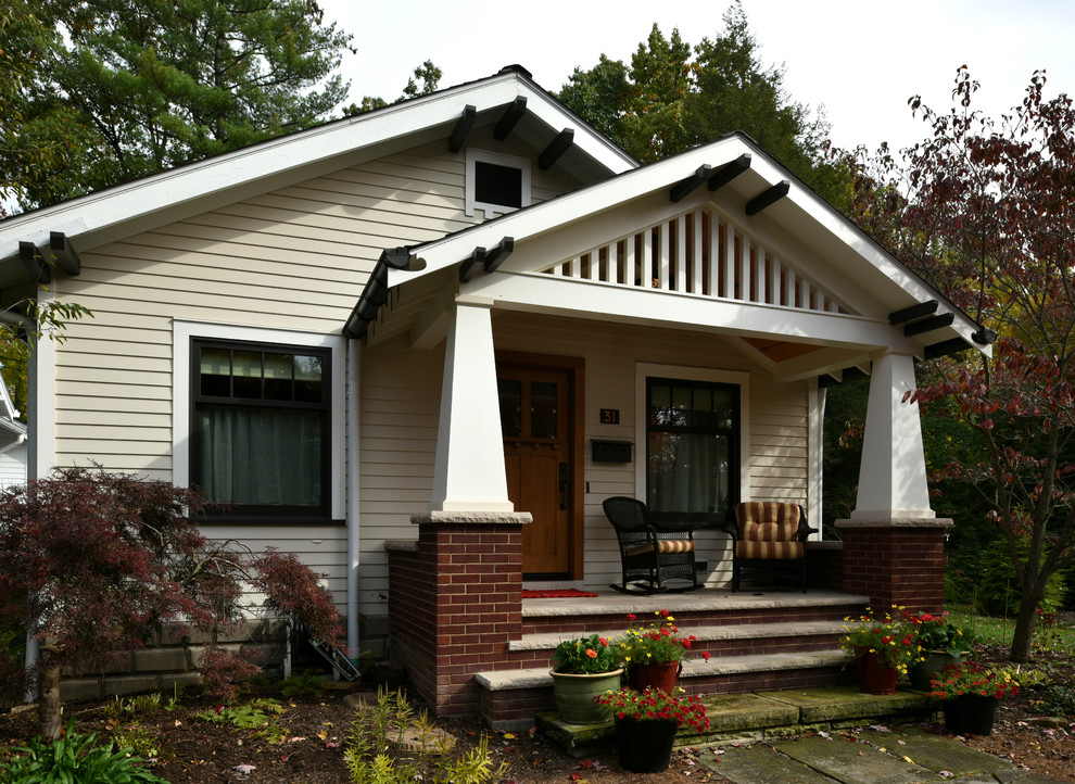 Foto på ett litet amerikanskt beige hus, med två våningar, fiberplattor i betong och sadeltak