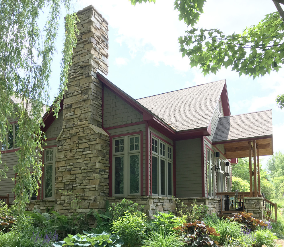 Immagine della facciata di una casa grande grigia american style a due piani con rivestimento in pietra e tetto a capanna