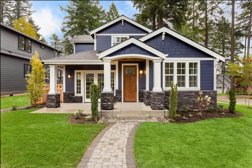 Стильный дизайн: двухэтажный, синий частный загородный дом среднего размера в стиле кантри с облицовкой из камня, двускатной крышей и крышей из гибкой черепицы - последний тренд