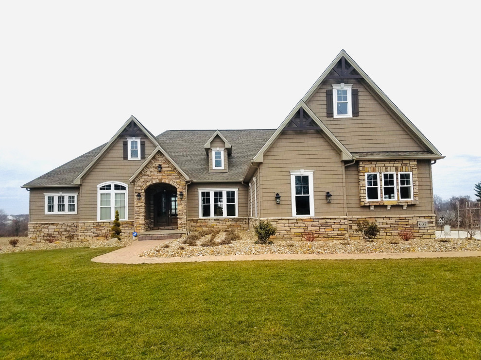 Large arts and crafts brown one-story stone exterior home photo in Cleveland with a shingle roof