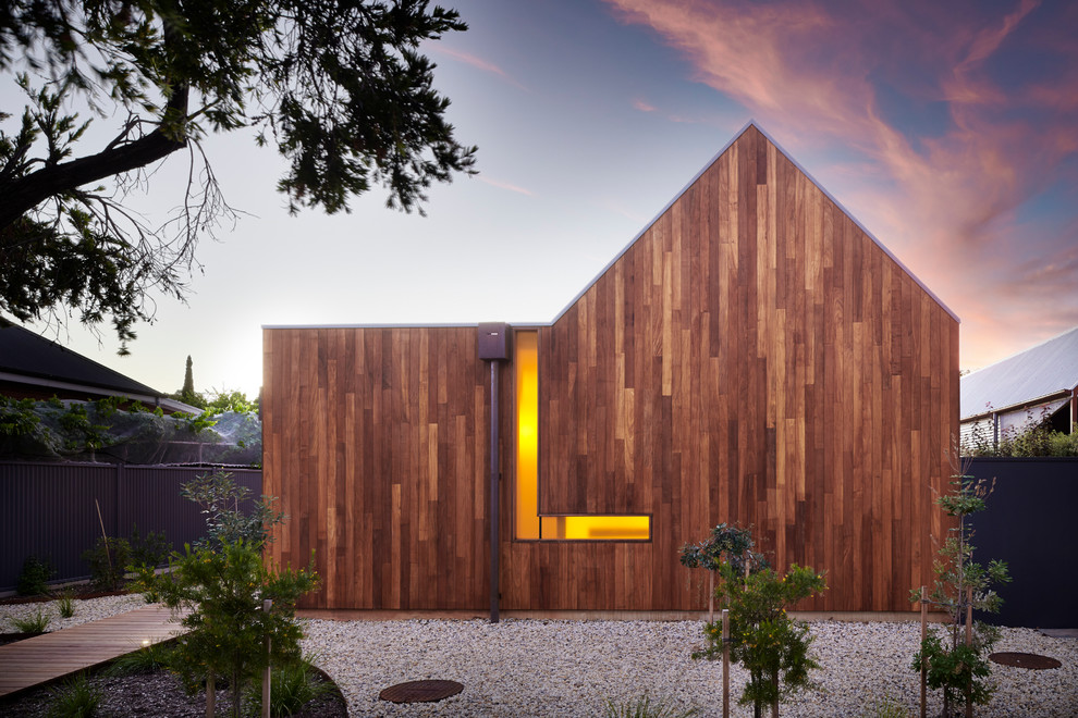 Foto della villa marrone contemporanea a un piano con rivestimento in legno e tetto a capanna