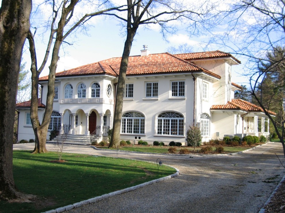 Aménagement d'une grande façade de maison blanche méditerranéenne à un étage avec un revêtement mixte, un toit de Gambrel et un toit en tuile.