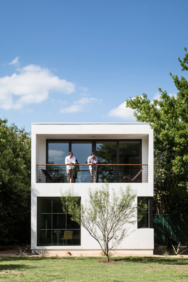 Réalisation d'une petite façade de maison blanche minimaliste en stuc à un étage avec un toit en appentis et un toit en métal.