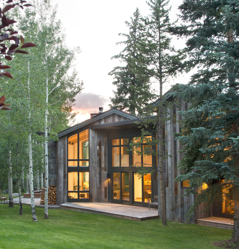 Idée de décoration pour une grande façade de maison grise design en bois à un étage avec un toit en appentis.