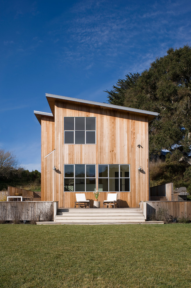This is an example of a medium sized farmhouse two floor house exterior in San Francisco with wood cladding and a lean-to roof.