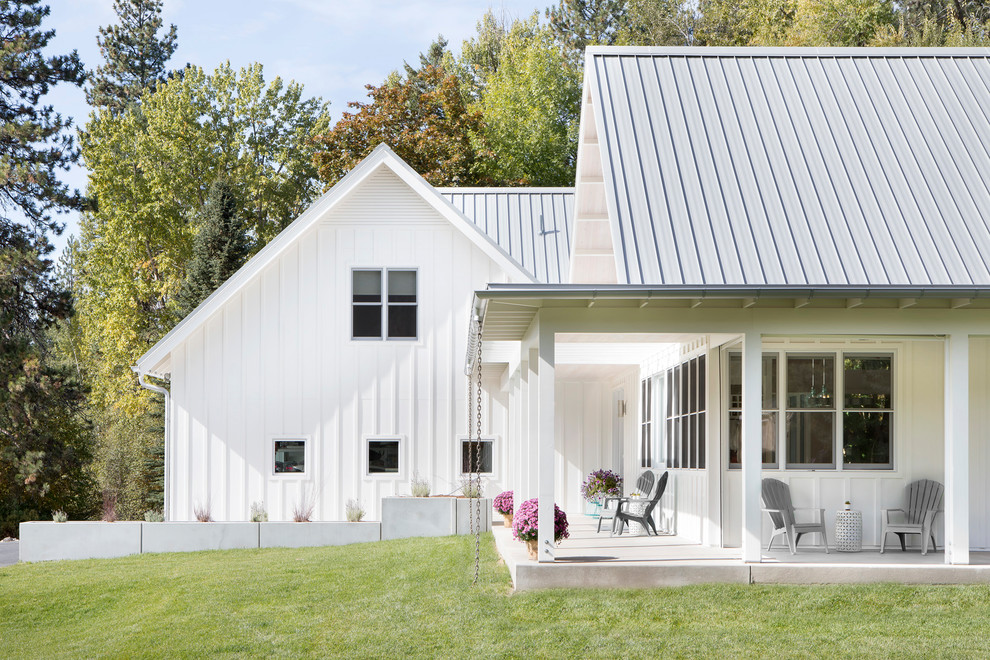 Foto della villa bianca country a un piano di medie dimensioni con rivestimento con lastre in cemento, tetto a capanna e copertura in metallo o lamiera