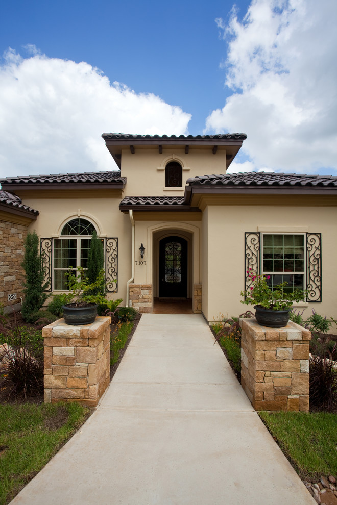 Photo of a medium sized and beige mediterranean bungalow house exterior in Austin with mixed cladding and a hip roof.