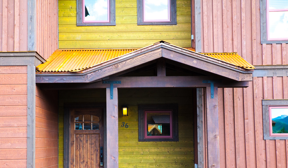На фото: большой, двухэтажный, деревянный, разноцветный частный загородный дом в стиле рустика с двускатной крышей и металлической крышей с