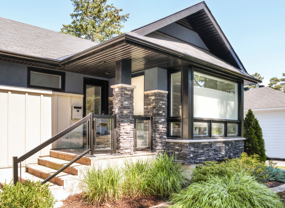 Photo of a black modern bungalow house exterior in Ottawa with stone cladding and a pitched roof.
