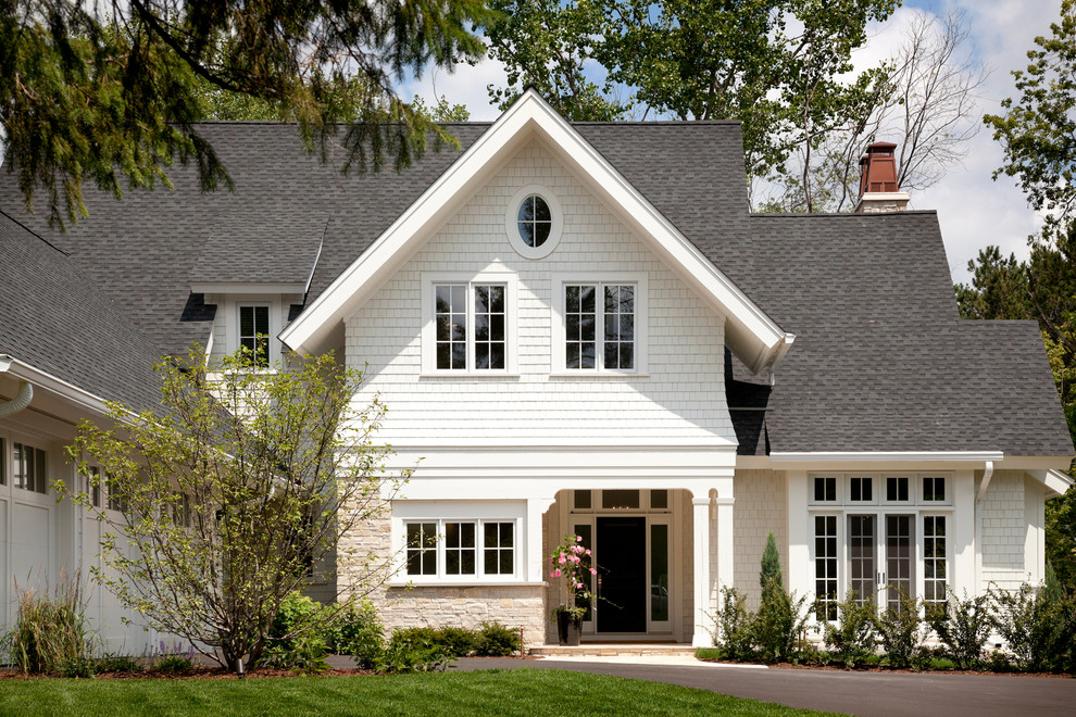 Immagine della facciata di una casa bianca classica a due piani con rivestimento in legno e tetto a capanna