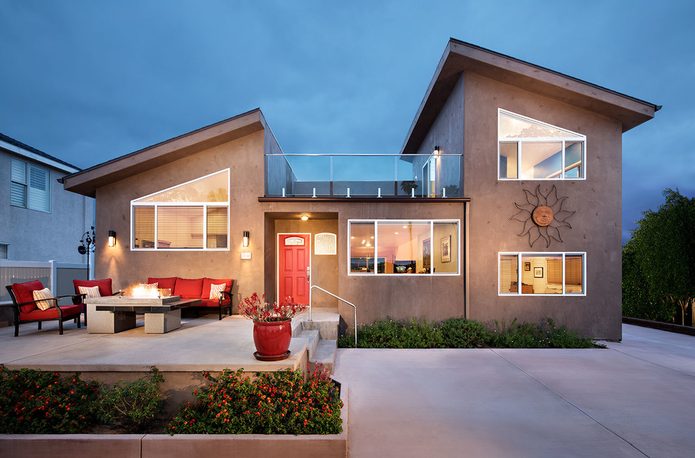 Diseño de fachada de casa beige actual de tamaño medio de dos plantas con tejado de un solo tendido y revestimiento de hormigón