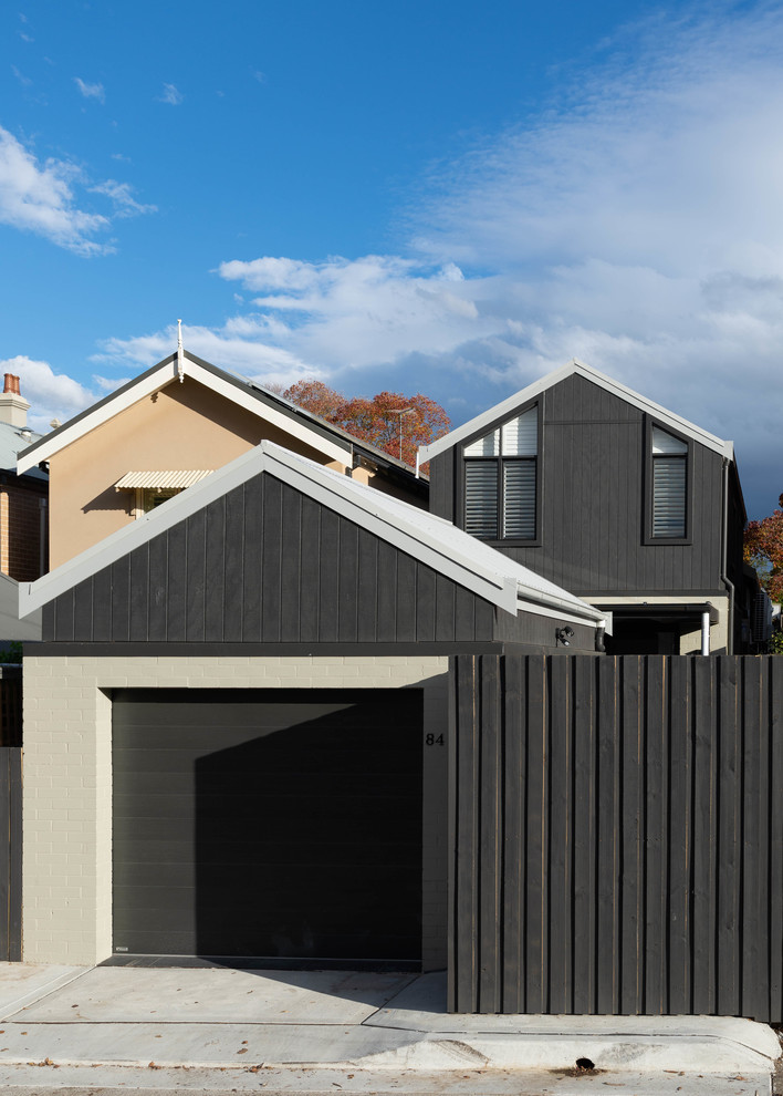 Kleines, Zweistöckiges Reihenhaus mit Faserzement-Fassade, schwarzer Fassadenfarbe, Satteldach und Blechdach in Sydney