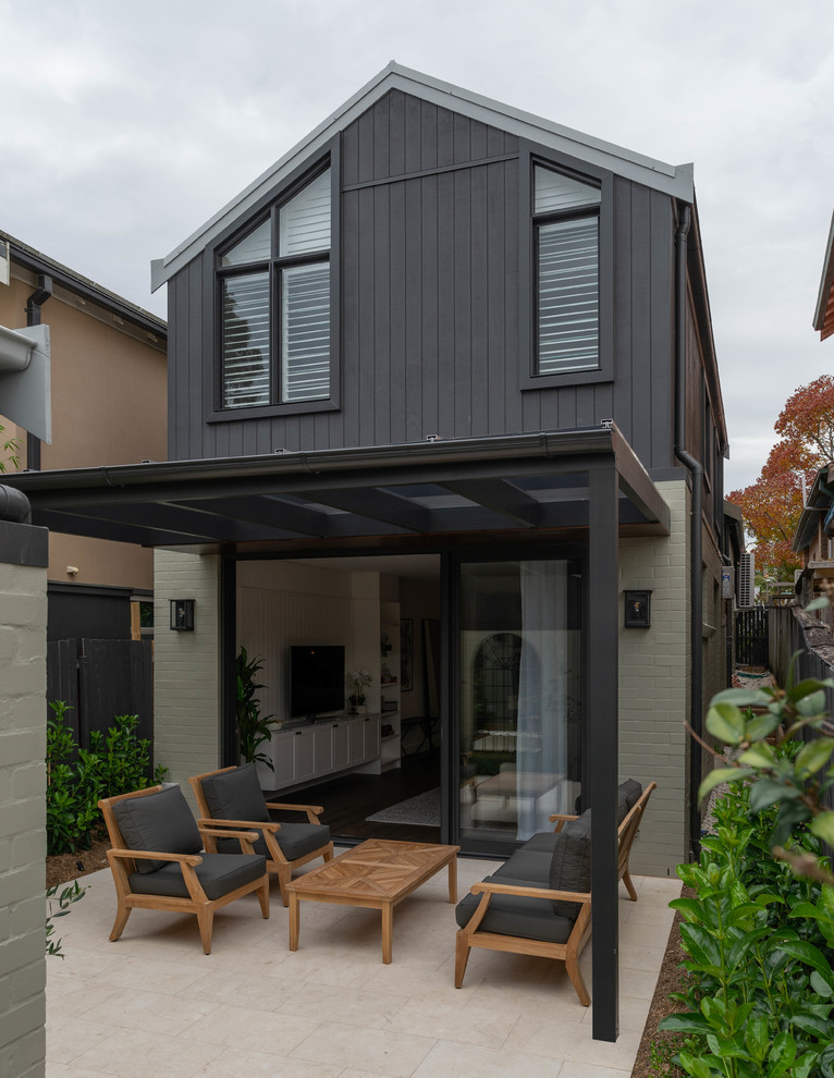 Photo of a small and black two floor terraced house in Sydney with concrete fibreboard cladding, a pitched roof and a metal roof.