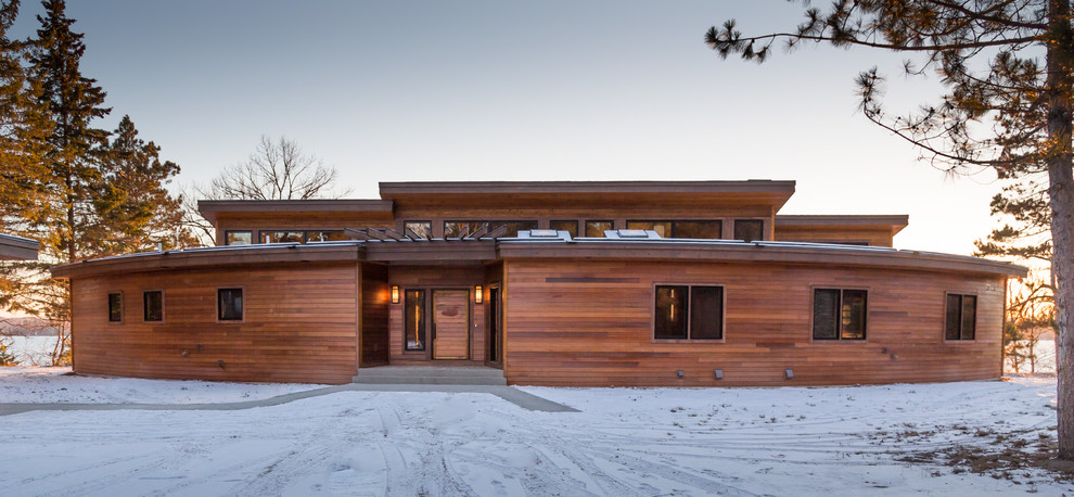 Cette photo montre une grande façade de maison marron montagne en bois à un étage avec un toit plat.