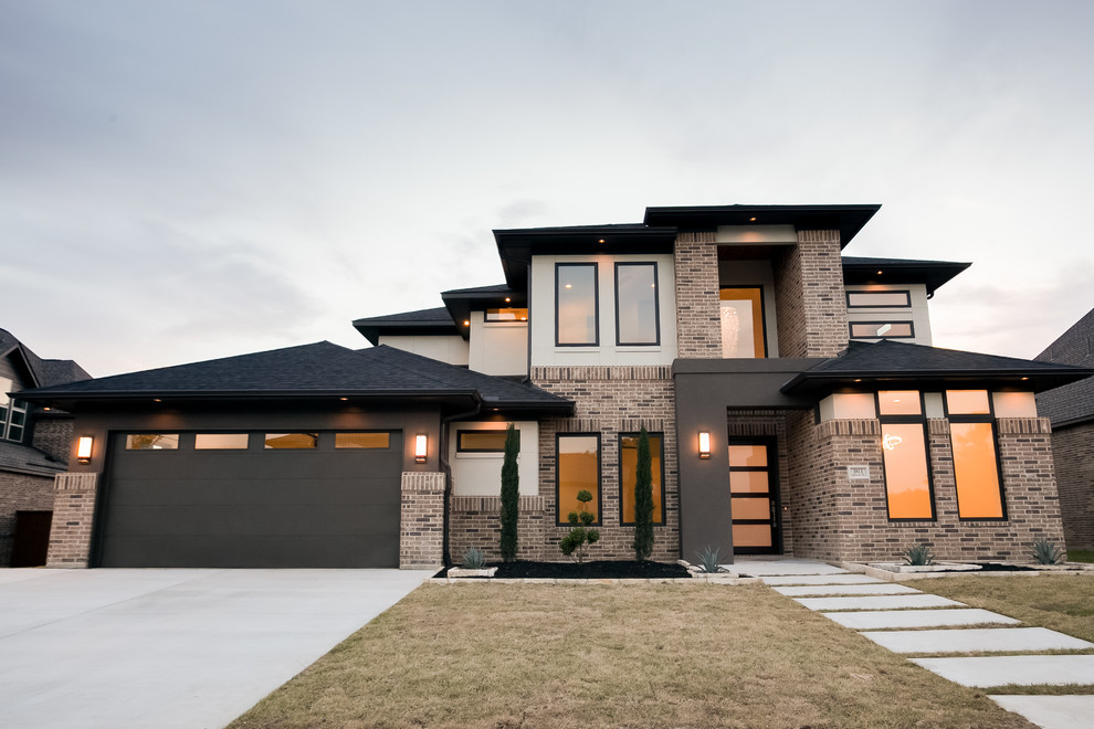 Cette image montre une grande façade de maison multicolore minimaliste en brique à un étage avec un toit à croupette et un toit en métal.