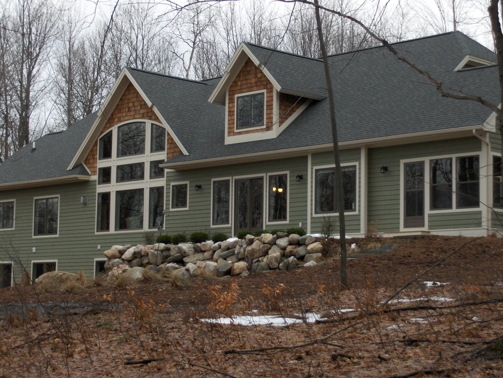 Imagen de fachada de casa verde de estilo americano grande de dos plantas con revestimiento de vinilo, tejado a dos aguas y tejado de teja de madera