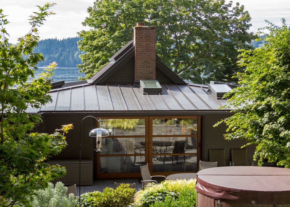 Réalisation d'une façade de maison grise design de taille moyenne et de plain-pied avec un toit à deux pans et un toit en métal.