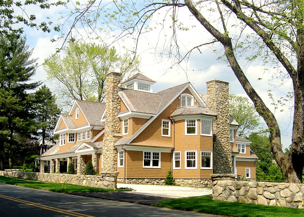Foto della facciata di una casa ampia marrone classica a tre piani con rivestimento in legno e tetto a capanna
