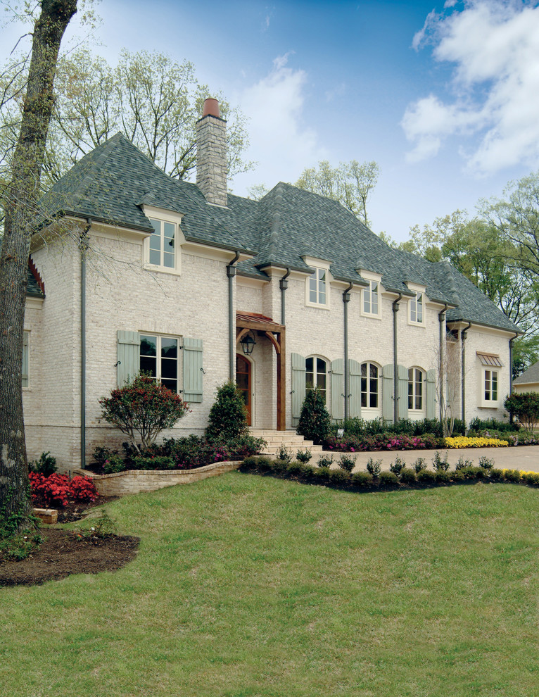 Exemple d'une grande façade de maison beige chic en brique à un étage avec un toit à quatre pans et un toit en shingle.