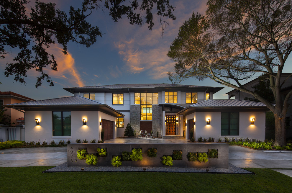 Diseño de fachada de casa beige actual grande de dos plantas con revestimiento de estuco, tejado a cuatro aguas y tejado de metal