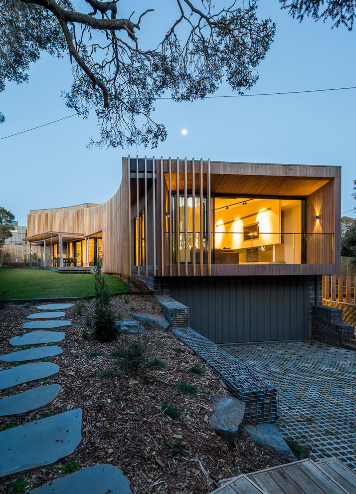 Идея дизайна: большой, деревянный, коричневый частный загородный дом в современном стиле с разными уровнями и плоской крышей