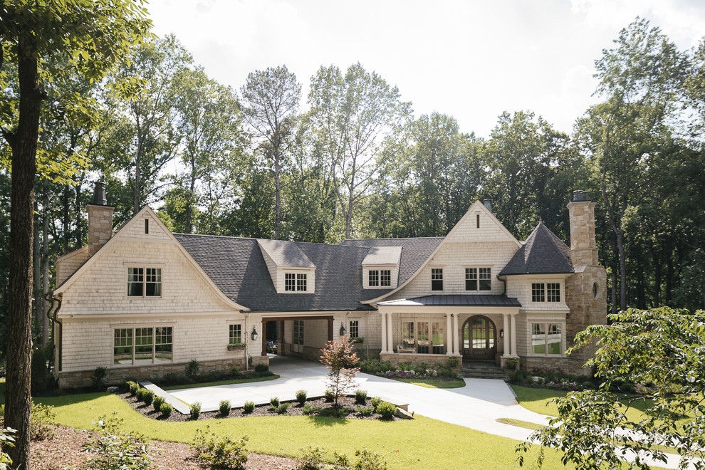 Ejemplo de fachada de casa beige de estilo americano grande de dos plantas con revestimiento de madera, tejado a cuatro aguas y tejado de teja de madera