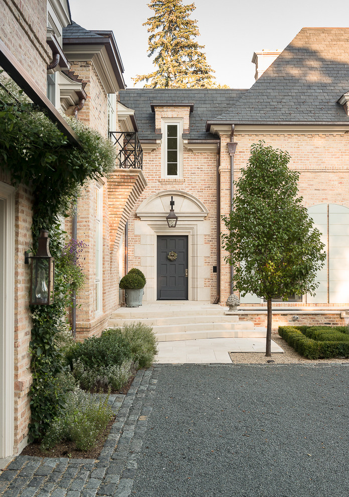 Diseño de fachada beige clásica grande de dos plantas con revestimiento de ladrillo y tejado a cuatro aguas