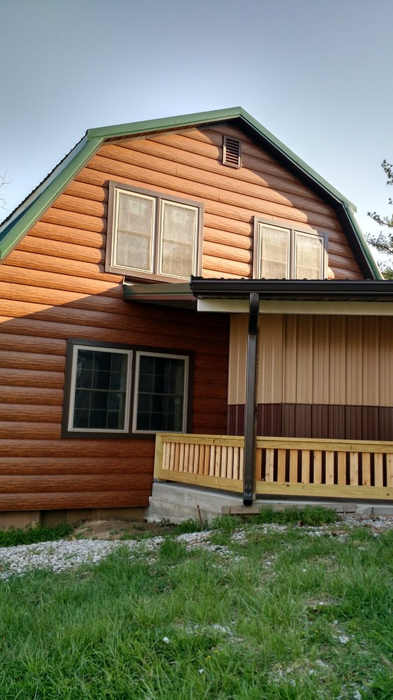 На фото: коричневый частный загородный дом в стиле рустика с облицовкой из металла с
