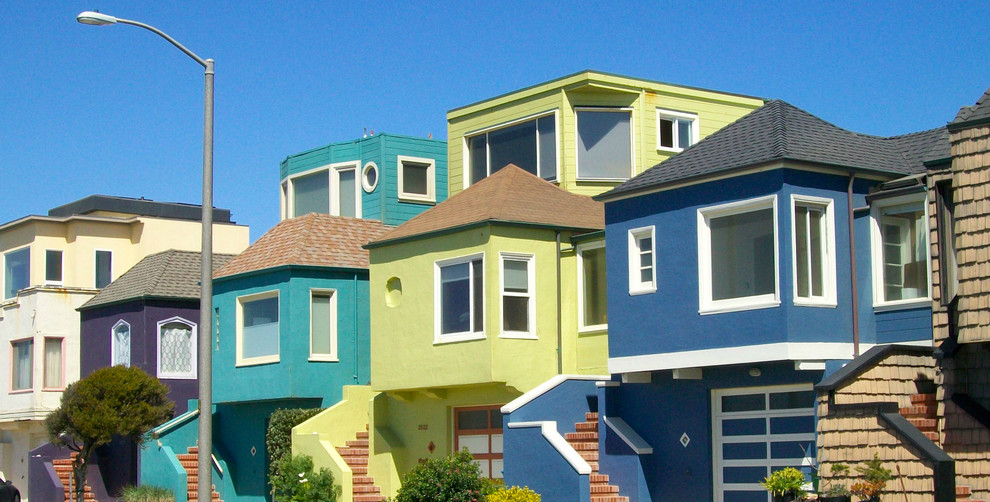 Exempel på ett mellanstort eklektiskt flerfärgat hus, med tre eller fler plan, stuckatur och valmat tak