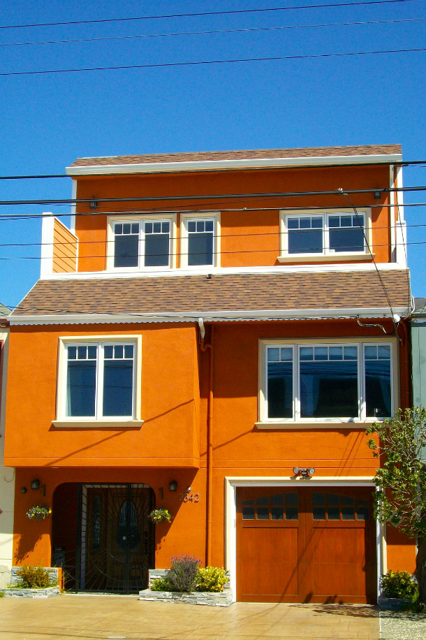 サンフランシスコにある中くらいなトランジショナルスタイルのおしゃれな三階建ての家 (漆喰サイディング、オレンジの外壁) の写真