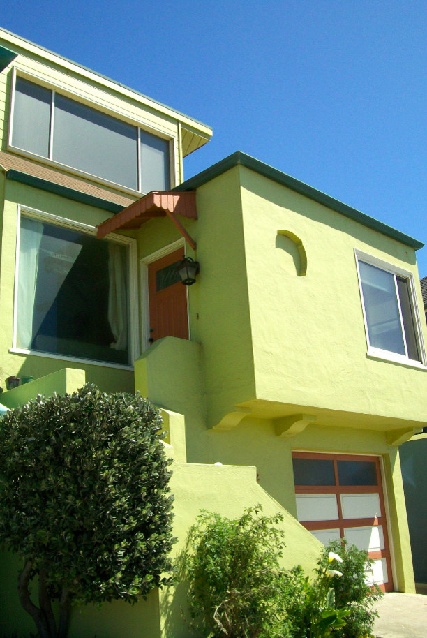 Réalisation d'une façade de maison verte bohème en stuc de taille moyenne et à un étage avec un toit plat.