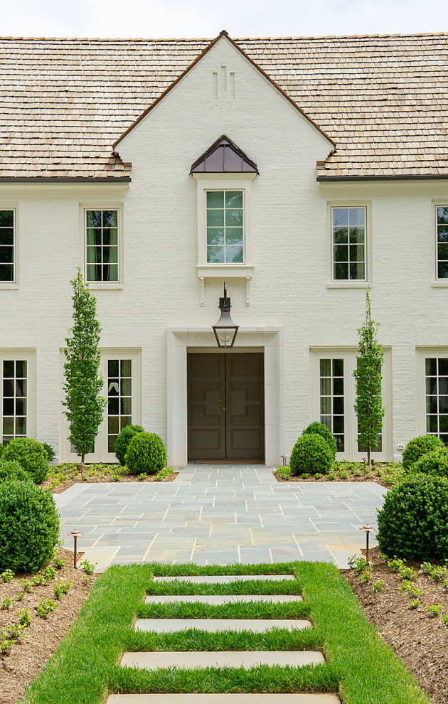 Imagen de fachada de casa blanca grande de dos plantas con revestimiento de ladrillo