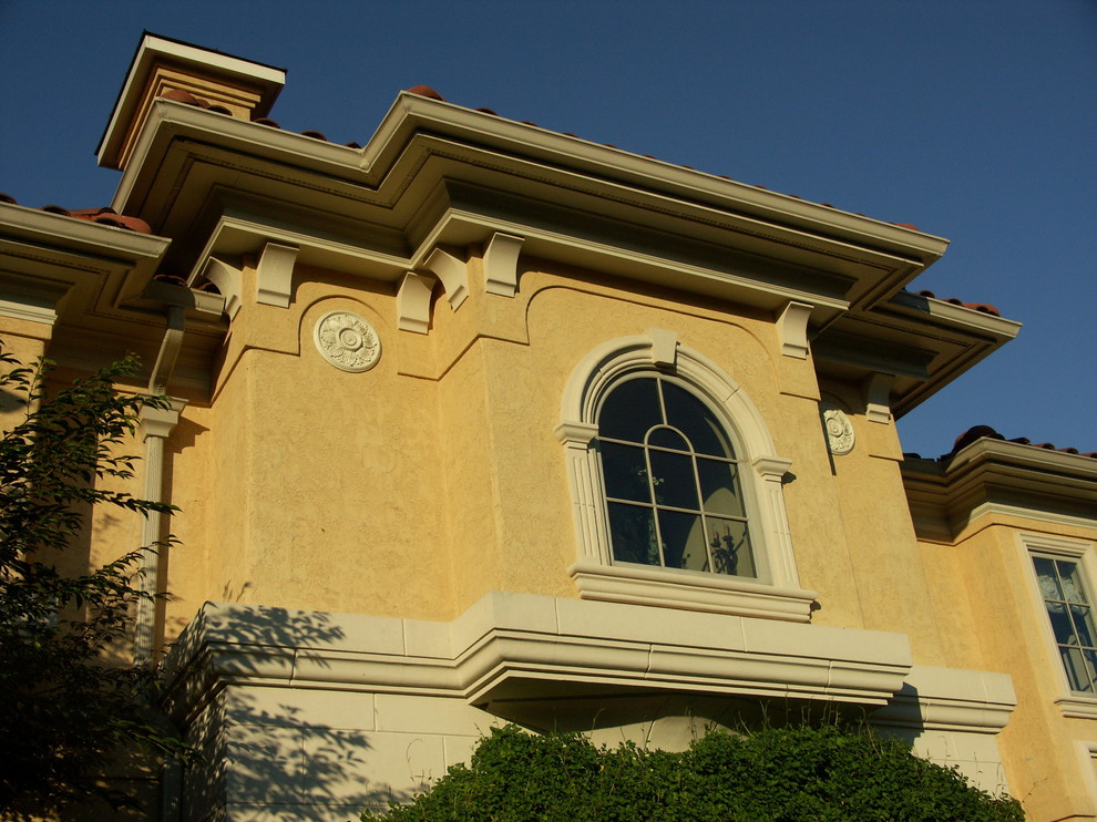 Idée de décoration pour une grande façade de maison beige tradition en stuc à deux étages et plus avec un toit à quatre pans.